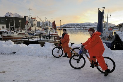 Norway, Nordland County, Vesteralen Islands, Myre harbour, young fishermen returning home by bike