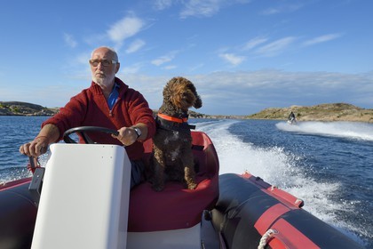 Sweden, Västra Götaland, Smögen, Cyril and his dog Simpson aboard his zodiac