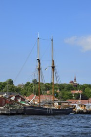 Sweden, Stockholm, old ship in the Beckholmen Island shipyard and the Hallestad belfry in the open air museum Skansen in the background