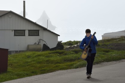 Groenland, cote ouest, Ile de Disko, Qeqertarsuaq, jeune inuit avec sa guitare et icebergs en arrière plan