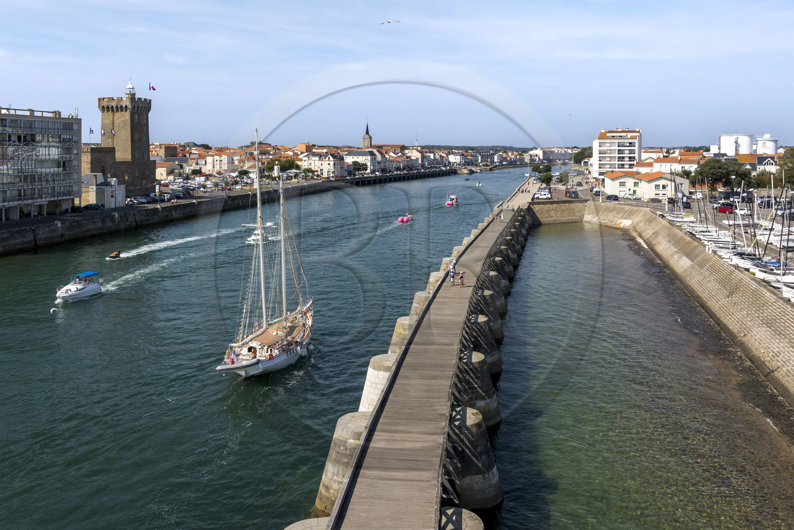 France, Vendee, Les Sables d'Olonne, boat in the access channel to the ports, the La Chaume district on the left with the 14th century Arundel Tower, a former keep converted into a lighthouse and maritime museum (aerial view)