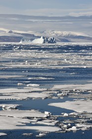 Groenland, cote Nord-Ouest, Smith sound au nord de la baie de Baffin, morceaux de glace de la banquise arctique et iceberg géant en arrière plan vers la côte canadienne de l'ile d'Ellesmere