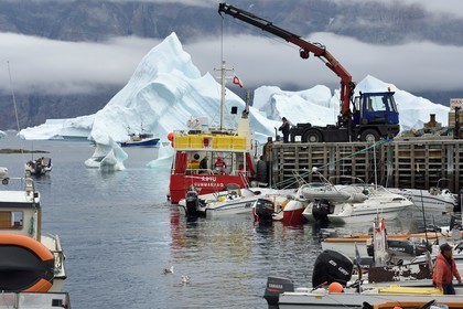 Groenland, cote ouest, Uummannaq, bateau de pêche déchargeant dans le port et icebergs en arrière plan
