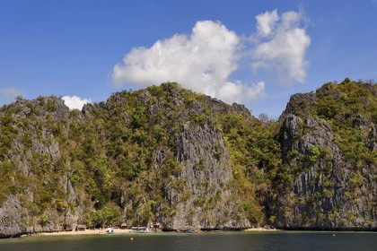 Philippines, Calamian Islands dans le nord de Palawan, Coron Island Natural Biotic Area, pirogue à balancier au pied des murs géants des falaises de calcaire