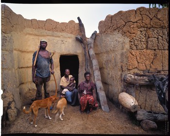 Burkina Faso, Poni province, Lobi land, Loropéni, peasant posing with bow and arrows with his two wives and his son in front of their house