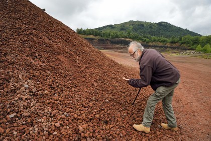 France, Puy de Dome, Parc Naturel Régional des Volcans d'Auvergne (regional nature park of Auvergne volcanoes), Chaine des Puys listed as World heritage by UNESCO, Saint Ours les Roches, Lemptegy volcano, a former quarry that has become an educational site open to the public, volcanologist Pierre Boivin observing pozzolana, a natural rock made up of basaltic volcanic slag