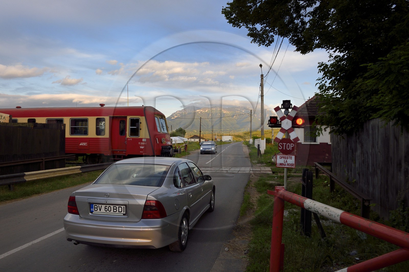Roumanie, Transylvanie, Zarnesti, train au passage à niveau et les monts Fagaras dans les Carpates du Sud