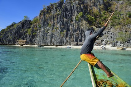 Philippines, Calamian Islands in northern Palawan, Coron Island Natural Biotic Area, Banul Beach under giant walls of limestone cliffs, boatman