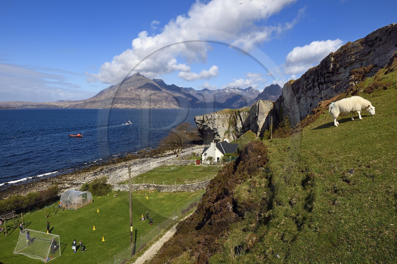 Royaume-Uni, Ecosse, région des Highlands, les Hébrides, Ile de Skye, village de Elgol sur les rives du Loch Scavaig au bout de la péninsule de Strathaird et le massif des Black Cuillin Mountains en arrière plan, enfants jouant au rounders dans le jardin de l'école