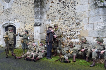 France, Eure, Chambray, Allied Reconstitution Group (US World War 2 and french Maquis historical reconstruction Association), reenactors in uniform of the 101st US Airborne Division and partisans of the French Forces of the Interior (FFI) resting in front of the church