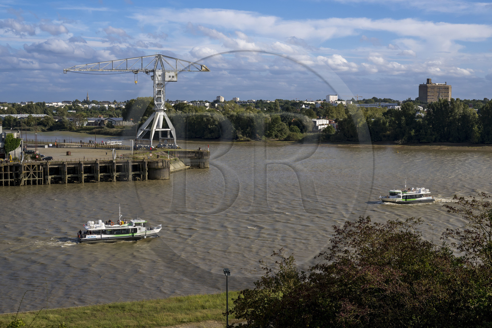France, Loire-Atlantique (44), Nantes, Ile de Nantes, le Navibus passant devant le Hangar à Bananes sur les quais de Loire, la Grue Titan grise et la Maison Radieuse de Le Corbusier en arrière plan, vue depuis les hauteurs de Chantenay
