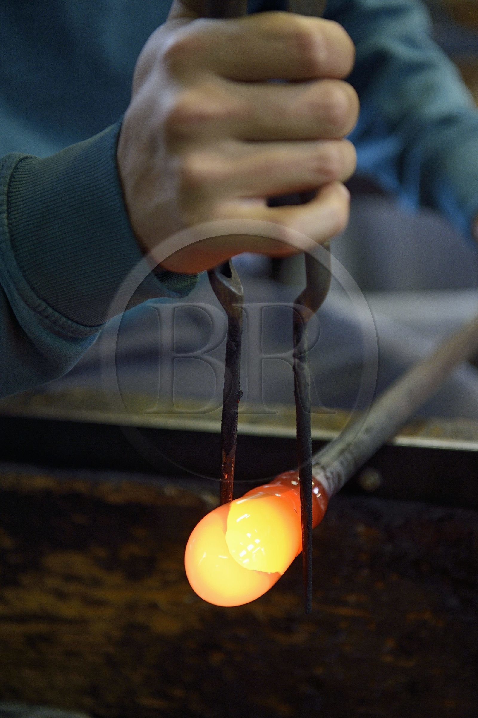 France, Moselle (57), Meisenthal, Centre international d’Art verrier (CIAV), l'atelier de soufflage, fabrication artisanale d'une boule de Noël, le souffleur régularise la masse au marbre tout en effectuant une rotation continue de sa canne France, Moselle (57), Meisenthal, Centre international d’Art verrier (CIAV), l'atelier de soufflage, fabrication artisanale d'une boule de Noël, le souffleur régularise la masse au marbre tout en effectuant une rotation continue de sa canne