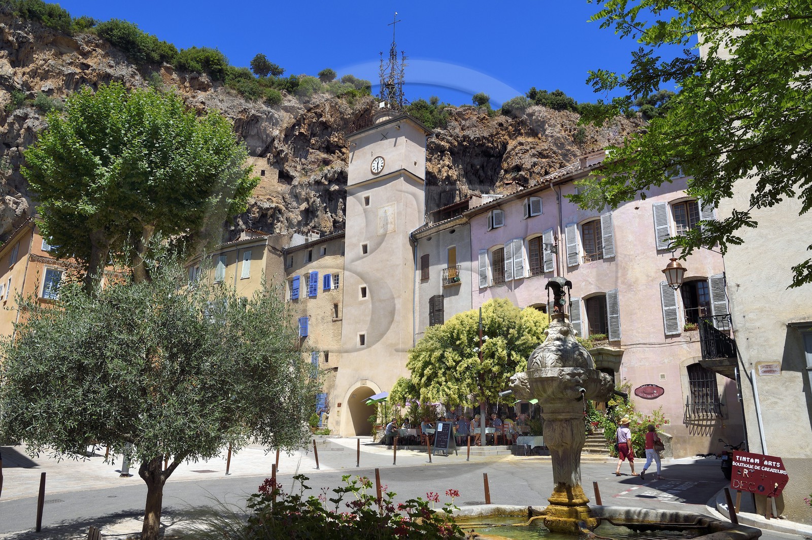 France, Var (83), Provence Verte, Cotignac, la Place de la Mairieet sa Tour de l'horloge en contrebas de la falaise de tuf de 80 mètres de haut et 400 mètres de large, fontaine de 1648 au premier plan