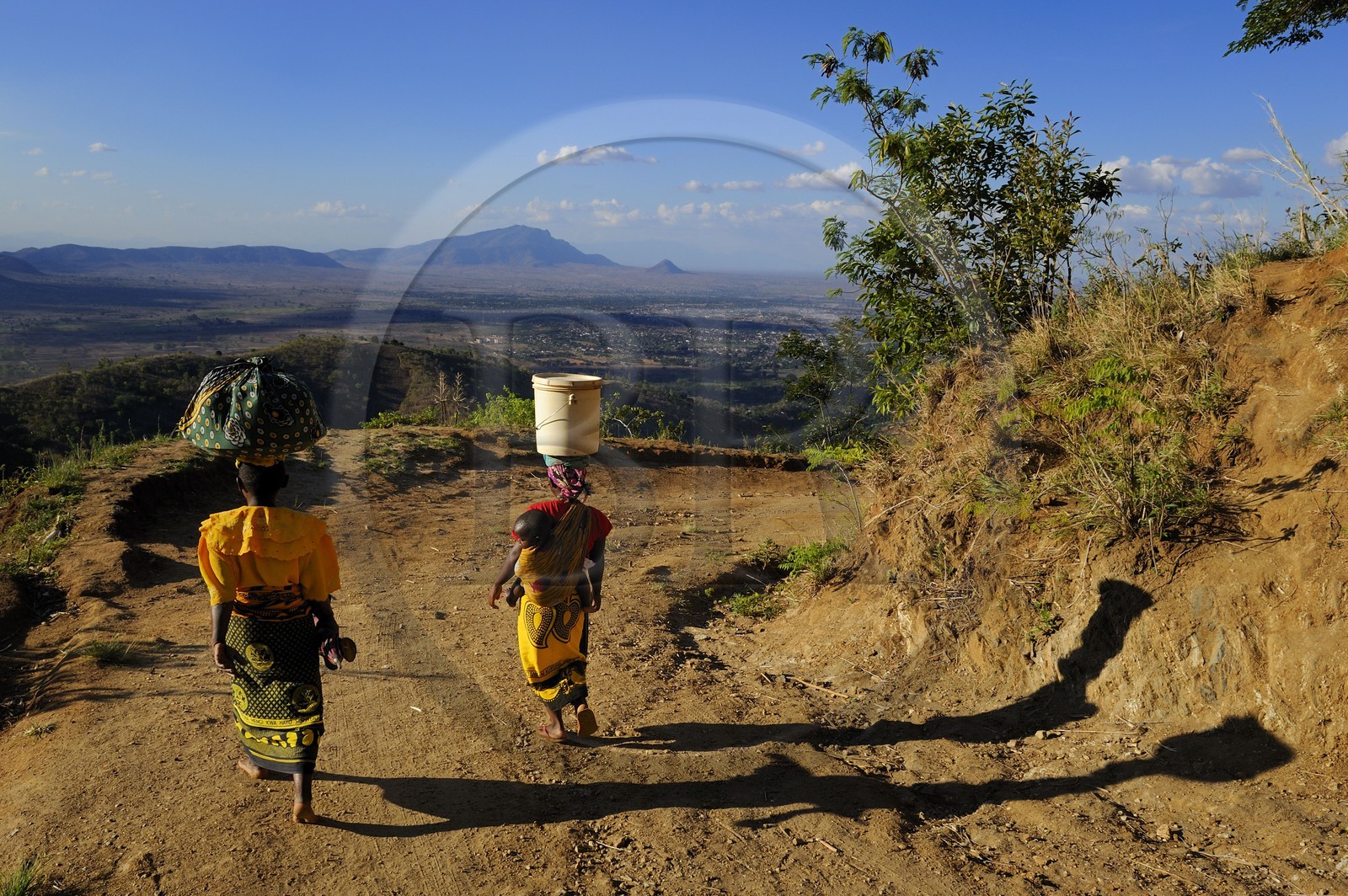 Tanzanie, région de Morogoro, les Monts Uluguru, aux alentours de l'ancien refuge allemand de Morningside, femmes avec un bébé dans le dos portant leurs provisions sur la tête, dans la plaine on aperçoit la ville de Morogoro