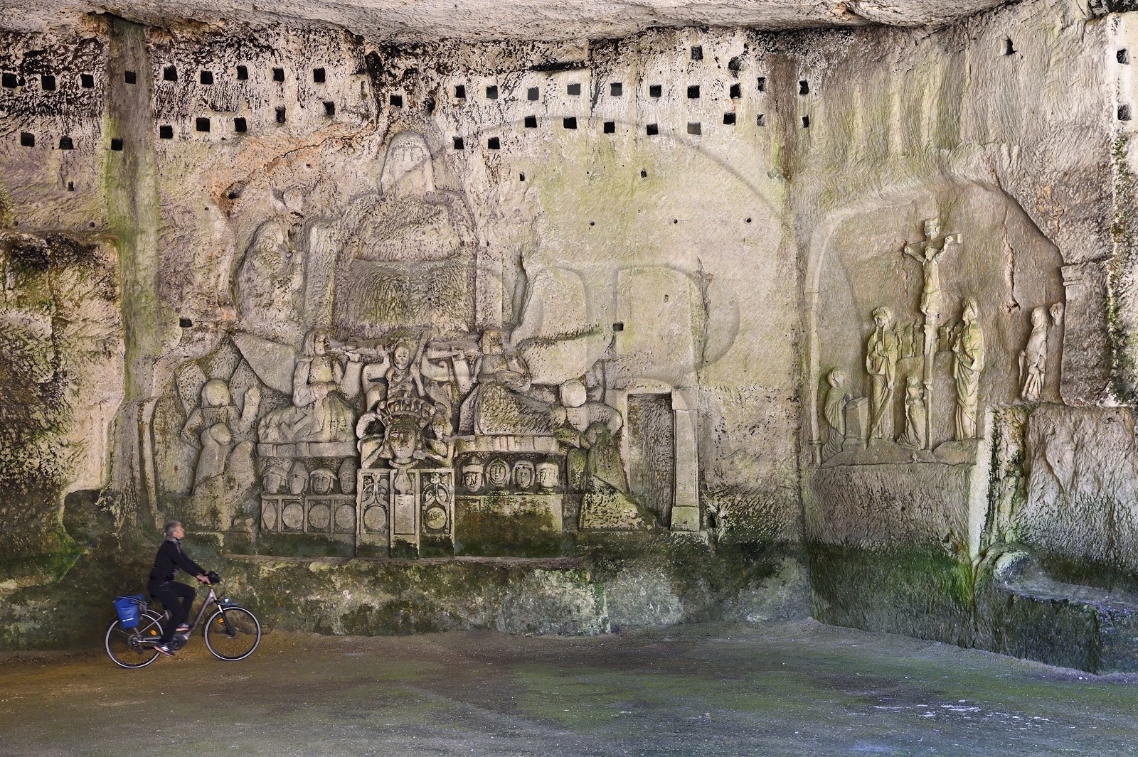 France, Dordogne (24), Brantôme, l'abbaye bénédictine Saint-Pierre de Brantôme, vestiges du premier monastère troglodytique aménagé dans les grottes au pied de la falaise avec notamment dans la grotte du Jugement Dernier, à droite la Crucifixion du début XVIIème siècle, à gauche un bas relief du XV ème siècle sous le pigeonnier, cycliste sur la véloroute la Flow Vélo