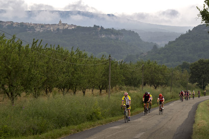 France, Vaucluse, Venasque, almond cultivation by the Silvain Brothers, nougat farmers, almond field, road bikers and the village of Venasque in the background