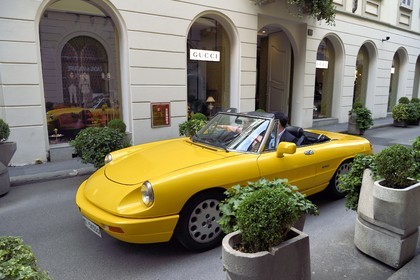 Italy, Lombardy, Milan, Fashion Quadrilateral (Quadrilatero della moda), Alfa Romeo Duetto Spider yellow cabriolet in front of the luxury boutique Gucci via Santo Spirito