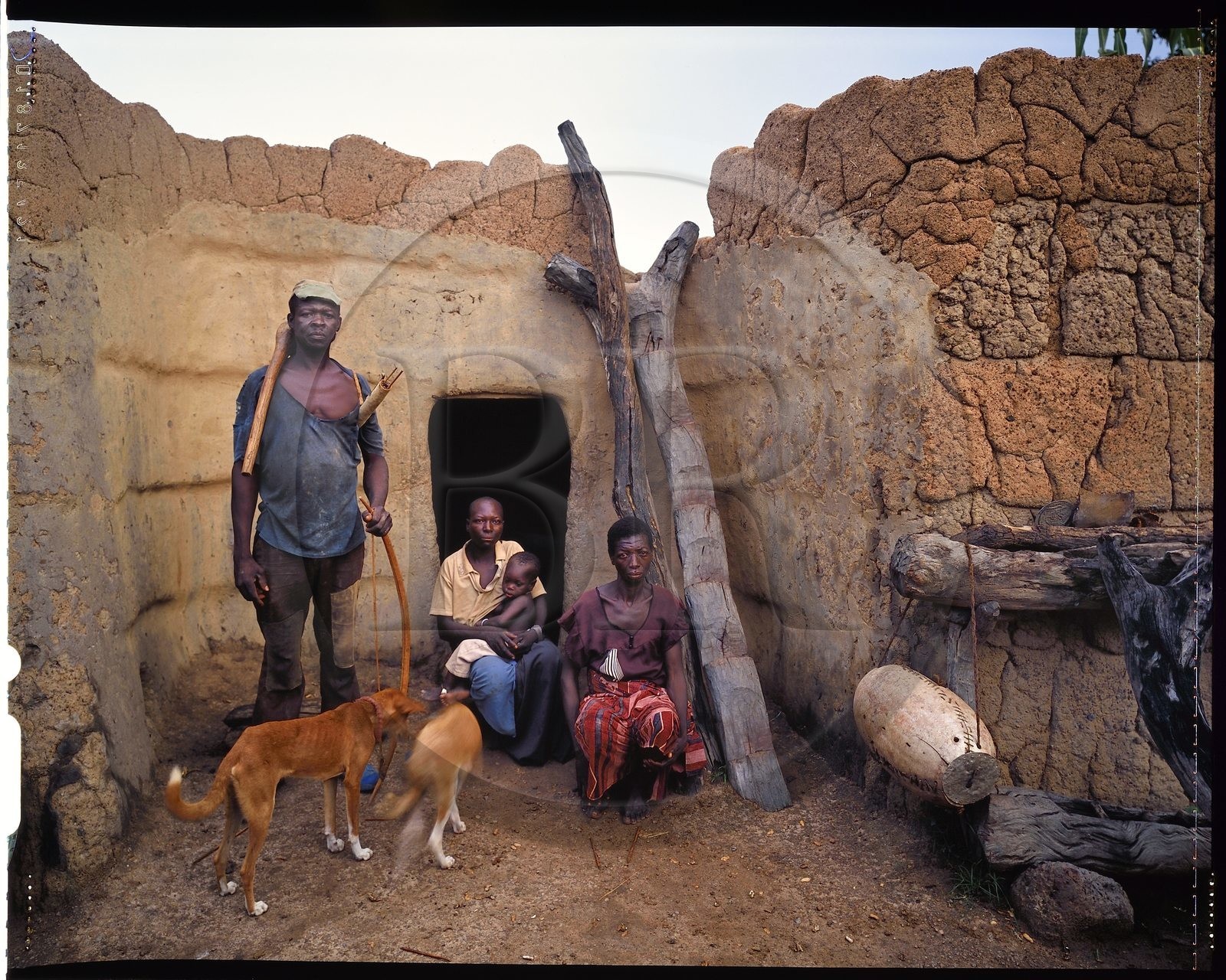 Burkina Faso, province de Poni, pays des Lobi, Loropéni, paysan posant avec arc et flèches avec ses deux épouses et son fils devant leur maison