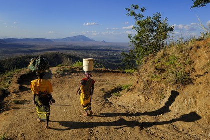 Tanzania, Morogoro district, Uluguru mountains, around the former german refuge called Morningside, women with a baby in the back carrying their supplies on their heads, in the plain we see the city of Morogoro