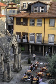 Portugal, Minho region, Guimaraes, town listed as World Heritage by UNESCO, gothic belvedere in front of the Church of Nossa Senhora da Oliveira on Largo da Oliveira square and cafe terrace