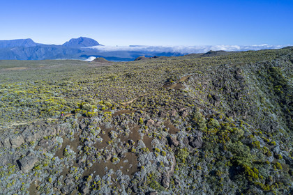 France, Ile de la Reunion, Parc National de la Réunion classé Patrimoine Mondial de l'UNESCO, sur les pentes du volcan de Piton de la Fournaise, randonneur sur le sentier de l'oratoire Ste Thérèse au dessus de la Plaine des Sables, le Piton des Neiges en arrière plan au nord (vue aérienne)