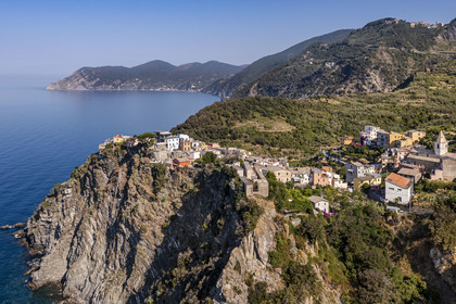 Italy, Liguria, Cinque Terre National Park listed as World Heritage by UNESCO, the village of Corniglia located at the top of a promontory overlooking the Mediterranean Sea at an altitude of about 100 m, the coast towards Monterosso in the background (aerial view)