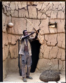 Burkina Faso, province de Poni, pays des Lobi, Loropéni, jeune Lobi devant la maison de son père avec les attributs des initiés: l'arc, le carquois et la houe