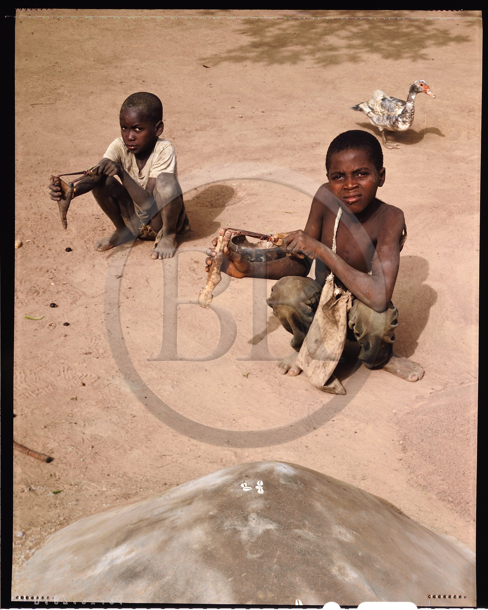 Burkina Faso, province de Poni, pays des Lobi, région de Loropéni, Ouadara, enfants avec lances-pierres derrière la tombe de leur frère, le lance-pierres est souvent la première arme du jeune lobi et ce jusqu'à son initiation Burkina Faso, province de Poni, pays des Lobi, région de Loropéni, Ouadara, enfants avec lances-pierres derrière la tombe de leur frère, le lance-pierres est souvent la première arme du jeune lobi et ce jusqu'à son initiation