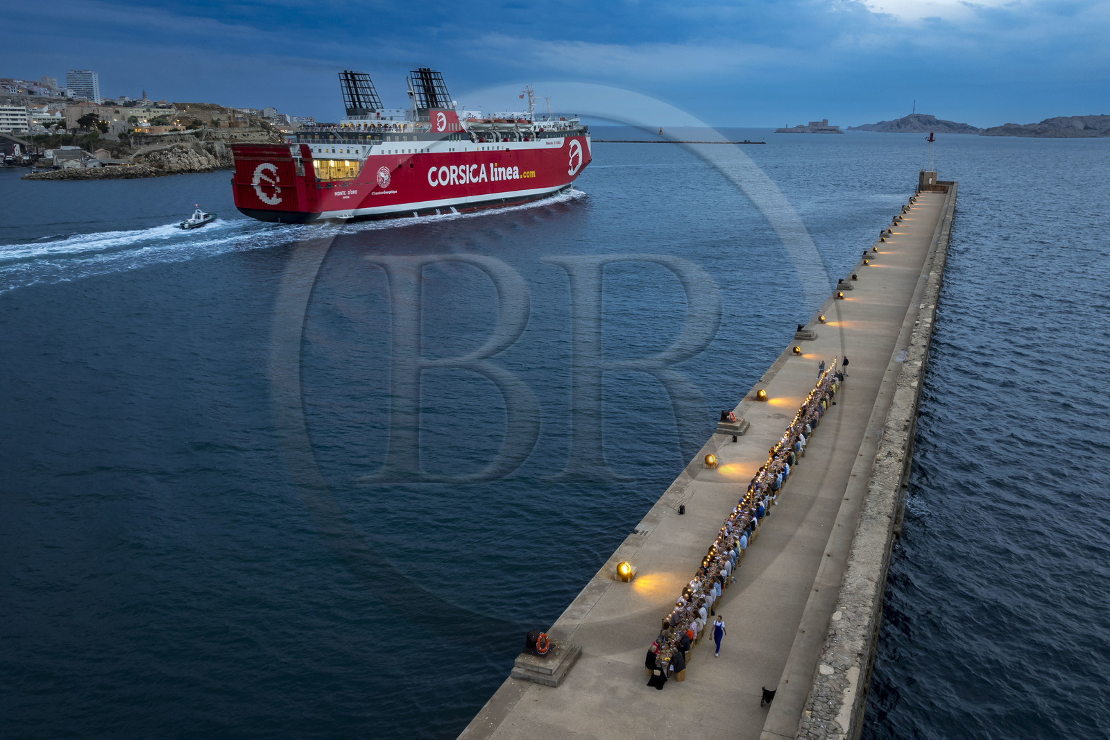 France, Bouches-du-Rhône (13), Marseille, Zone Euroméditerranée, grand port maritime de Marseille (GPMM), la digue du large, convives attablés à une grand table de banquet dressée par le chef Emmanuel Perrodin dans le cadre des Diners Insolites, un ferry de Corsica Linea quitte le port, l’Archipel des îles du Frioul avec le Chateau d'If en arrière plan (vue aérienne)