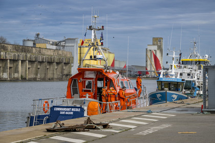France, Loire-Atlantique, Saint-Nazaire, commercial port, SNSM (Société Nationale de Sauvetage en Mer) boat with its crew in the floating dock and the former German submarine base built during the last world war in the background