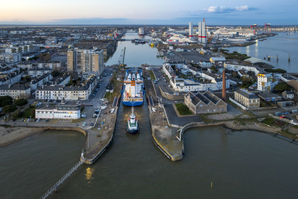 France, Loire Atlantique, Saint Nazaire, The General Cargo Rotra Mare transports sections of wind turbine masts and enters the port's wet dock (in the background) via the south lock, which was also the site of Operation Chariot launched in 1942 by the British (aerial view)
