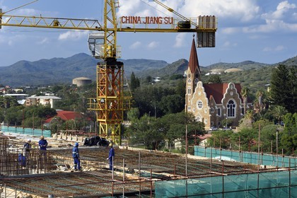 Namibie, région de Khomas, Windhoek, immeuble en construction par une société chinoise et la Christ Church (or Christuskirche) en arrière plan