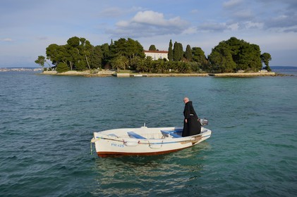 Croatia, Dalmatia, Dalmatian Coast, Ugljan Island, Preko, Franciscan friar Bozo Susic leaving the Franciscan Monastery of the Galovac island on his boat