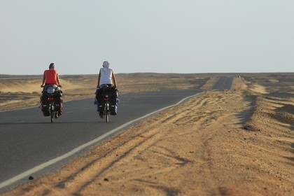 Egypt, Libyan desert, couple of cycling tourists on the road from Cairo to Bahareyya