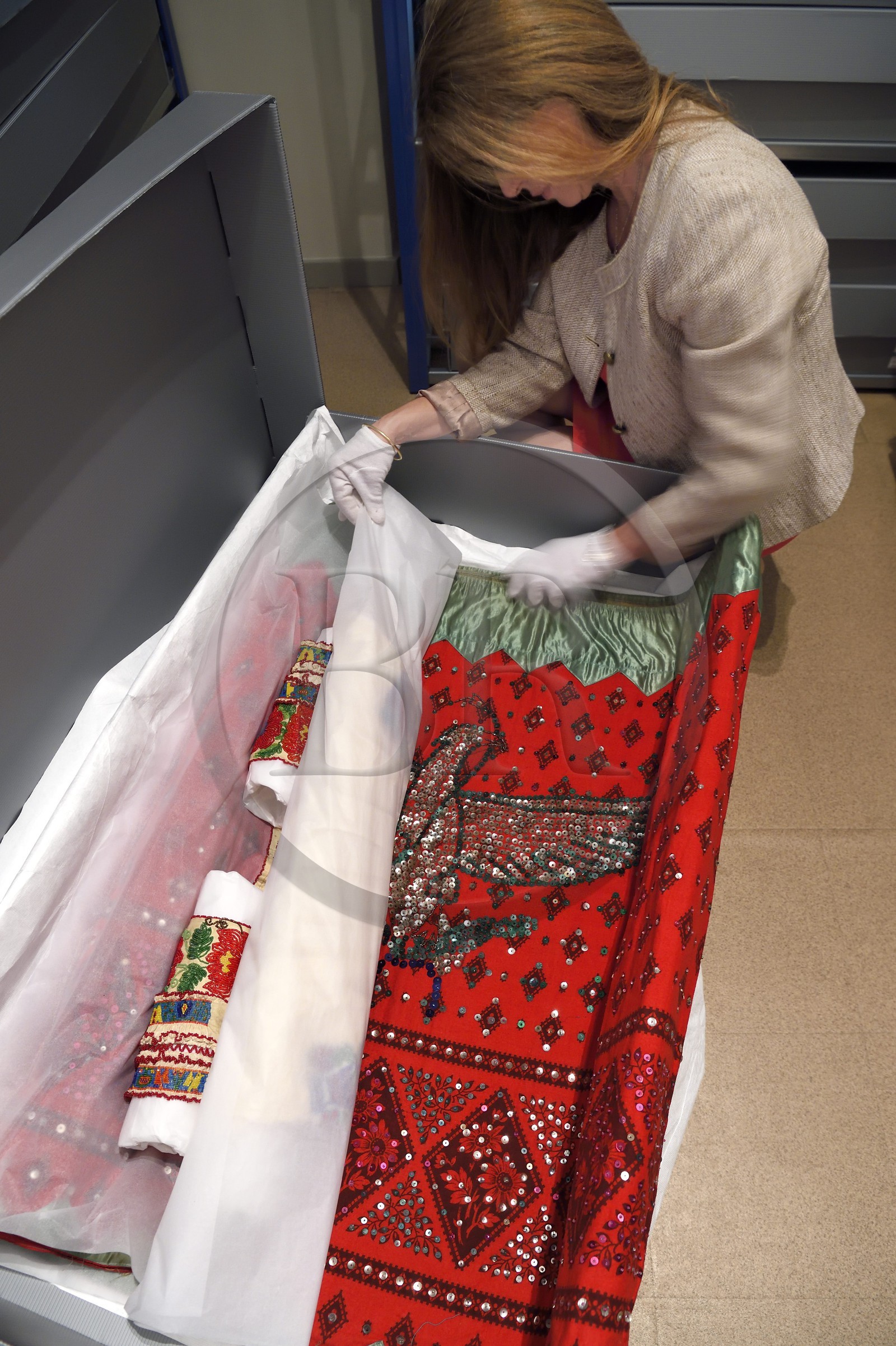 France, Alpes-de-Haute-Provence (04), vallée de l'Ubaye, Barcelonnette, villa mexicaine connue sous le nom de Villa Sapinière, Musée de la vallée, la conservatrice Hélène Homps dans la réserve du musée observe une robe brodée China poblana, costume national mexicain porté par les épouses des barcelonnettes pour le 14 juillet au Mexique