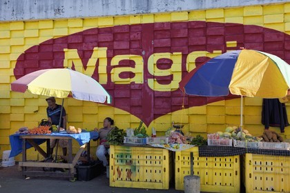 Caribbean, Dominica Island, the capital city Roseau, central market, fruit and vegetable stall in front of an advertising wall mural for Maggi