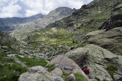 France, Alpes-Maritimes, parc national du Mercantour (Mercantour National Park), hiker on the trail GR 52, the Vallee des Merveilles (Valley of Wonders) scattered with thousands of rupestral engravings of the Bronze Age and the Paroi vitrifiée in the background