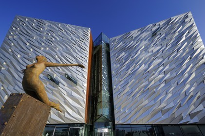 United Kingdom, Northern Ireland, Belfast, docks district of Queen's Island, Titanica sculpture by artist Rowan Gillespie in front of the Titanic Belfast Experience center building