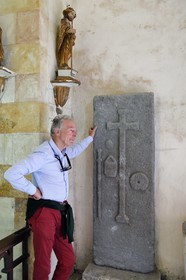 France, Cantal, step on the Way of St. James to Santiago de Compostela by Via Arverna, Neussargues-Moissac, 12th century Saint-Hilaire church, tomb of a 17th century pilgrim who made the way to St Jacques de Compostela, tombstone with the bumblebee, the sack and the shell around the funeral cross, the chief heritage curator Humbert Jacomet