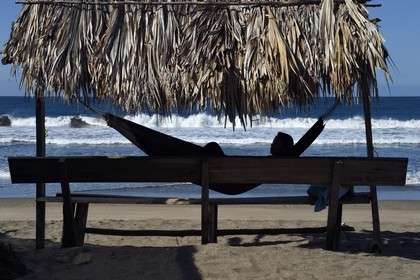 Nicaragua, the Pacific coast of Leon, Isla Juan Venado Nature Reserve, Woman in a hammock on the beach