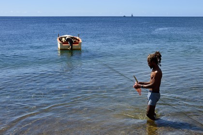 Caraïbes, Ile de la Dominique, baie de Soufrière, un pêcheur nettoie son poisson sur la plage de Soufrière