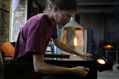 France, Moselle (57), Meisenthal, Thibaut souffleur au Centre international d’Art verrier (CIAV) s’aide d’une mailloche en bois pour arrondir le verre et faire une boule de Noël en verre régulière