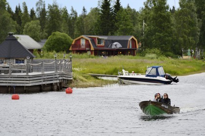 Sweden, Vasterbotten County, Umea, boat going up the Ume River (Umeälven) and wooden house