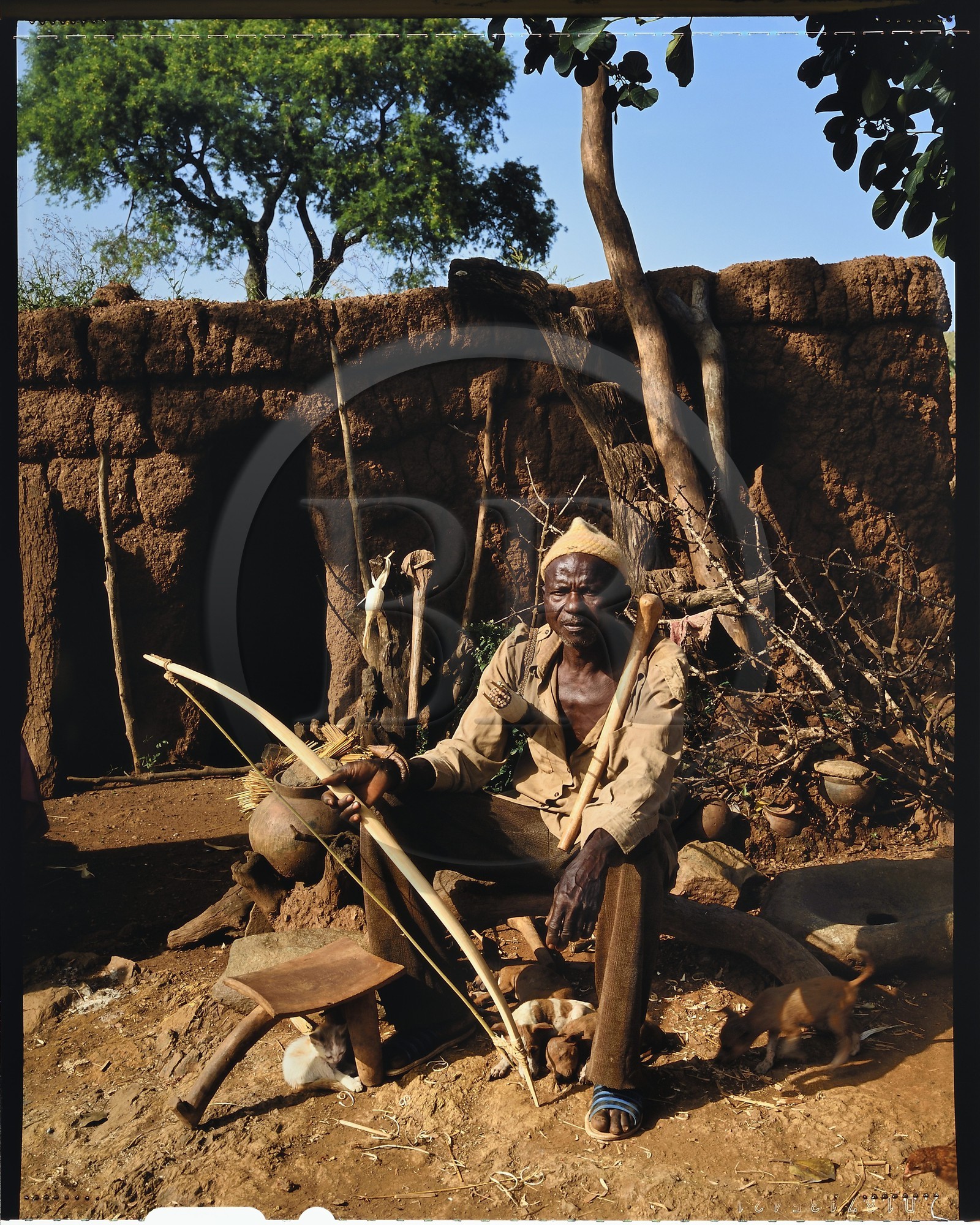 Burkina Faso, Poni province, Lobi land, Loropéni, farmer and hunter in his yard posing with the attributes of the initiates: the bow, the quiver and the hoe