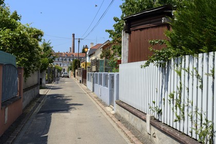 France, Haut Rhin, Mulhouse, la Cite ouvriere (working class housing), passage des Corbeaux and brick chimney of the textile company DMC (Dollfus-Mieg et Compagnie) in the background