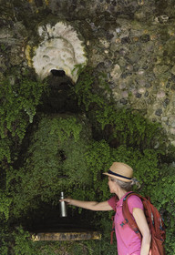 Italie, Ligurie, Cinque Terre, parc national des Cinque Terre classé Patrimoine Mondial de l'UNESCO, randonneuse remplissant sa gourde à la fontaine du sanctuaire de Nostra Signora di Reggio sur les hauteurs du village de Vernazza