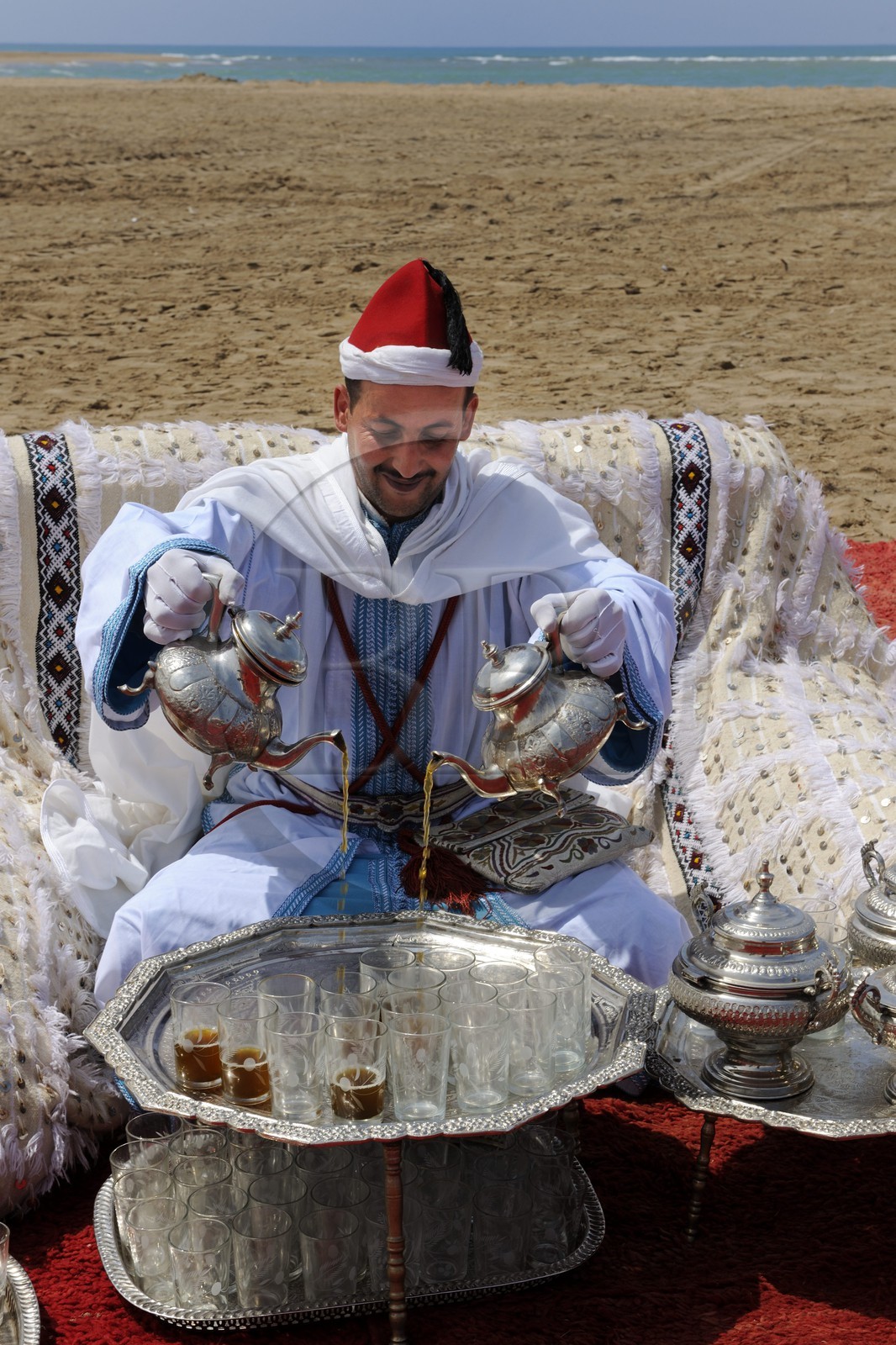 Maroc, région de l'Oriental, service du thé à la menthe en costume d'apparat sur une plage