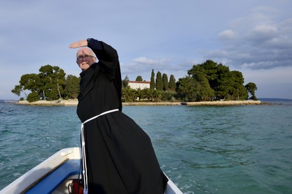 Croatia, Dalmatia, Dalmatian Coast, Ugljan Island, Preko, Franciscan friar Bozo Susic leaving the Franciscan Monastery of the Galovac island on his boat