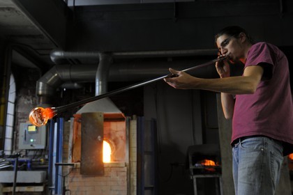 France, Moselle (57), Meisenthal, Thibaut souffleur au Centre international d’Art verrier (CIAV), fabrication d'une boule de Noël en verre. Tout en tournant la canne, il souffle dans la canne
