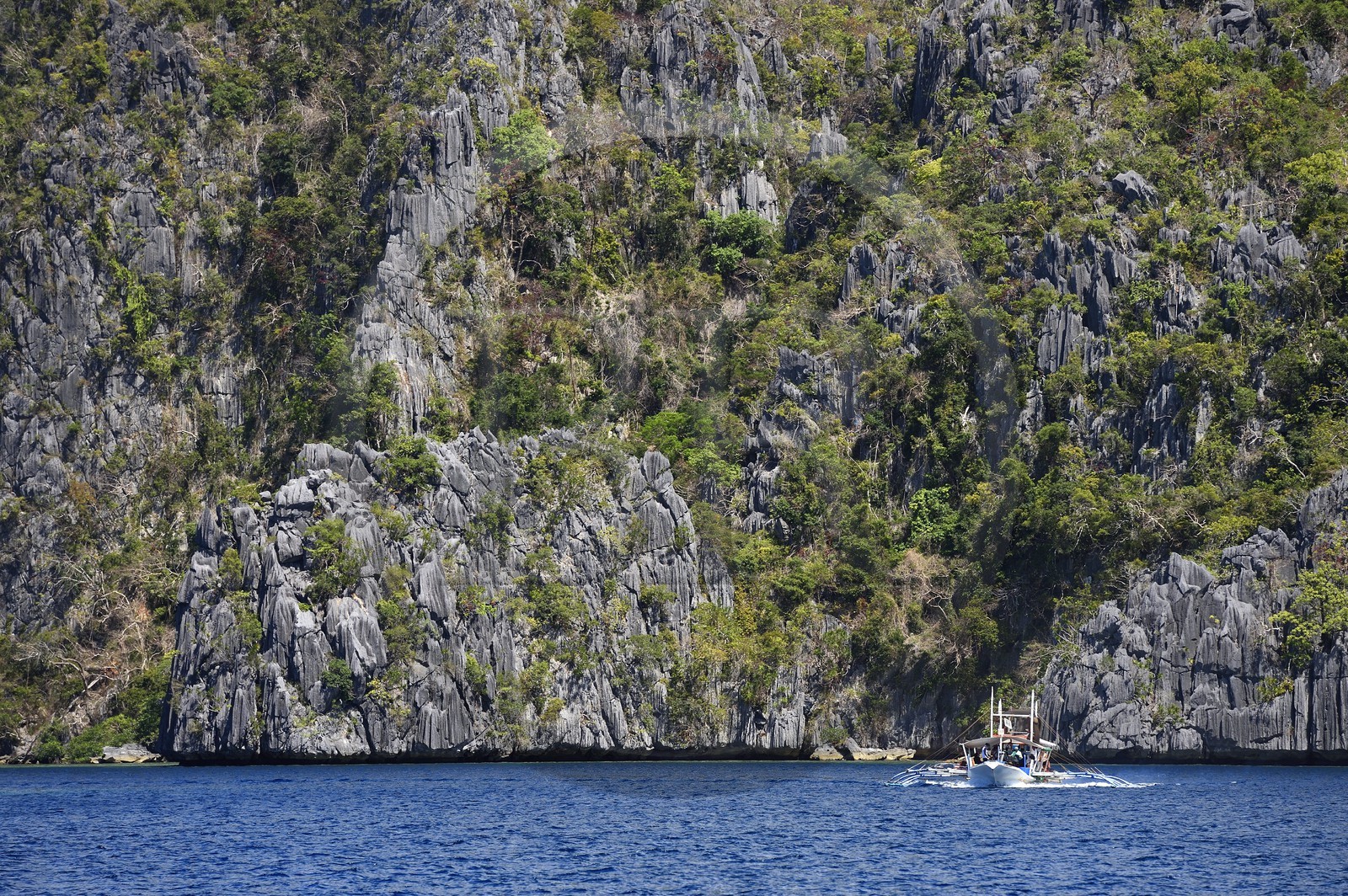 Philippines, Calamian Islands dans le nord de Palawan, Coron Island Natural Biotic Area, pirogue à balancier au pied des murs géants des falaises de calcaire